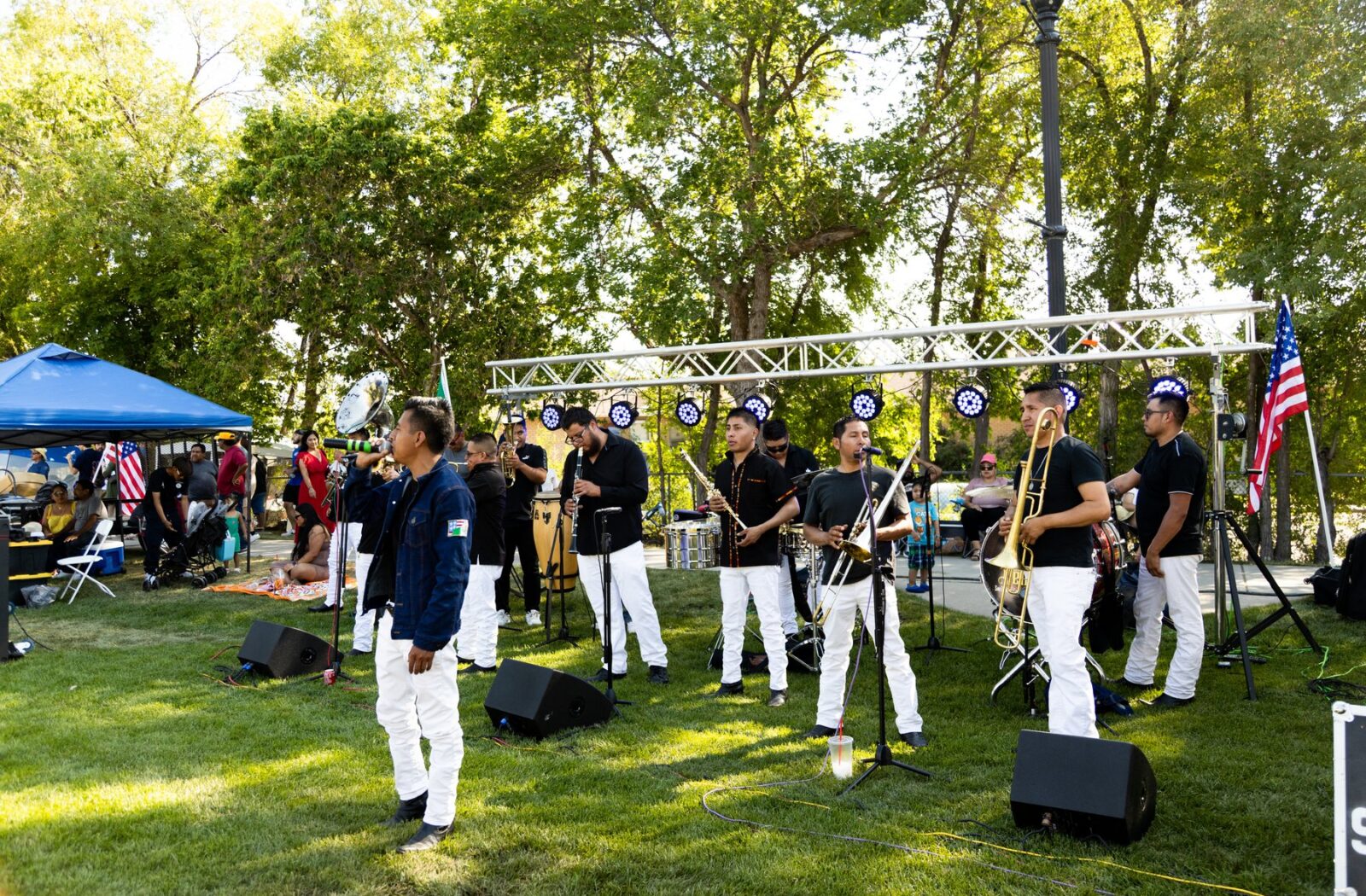 Un conjunto de metales con camisas negras y pantalones blancos toca bajo los árboles