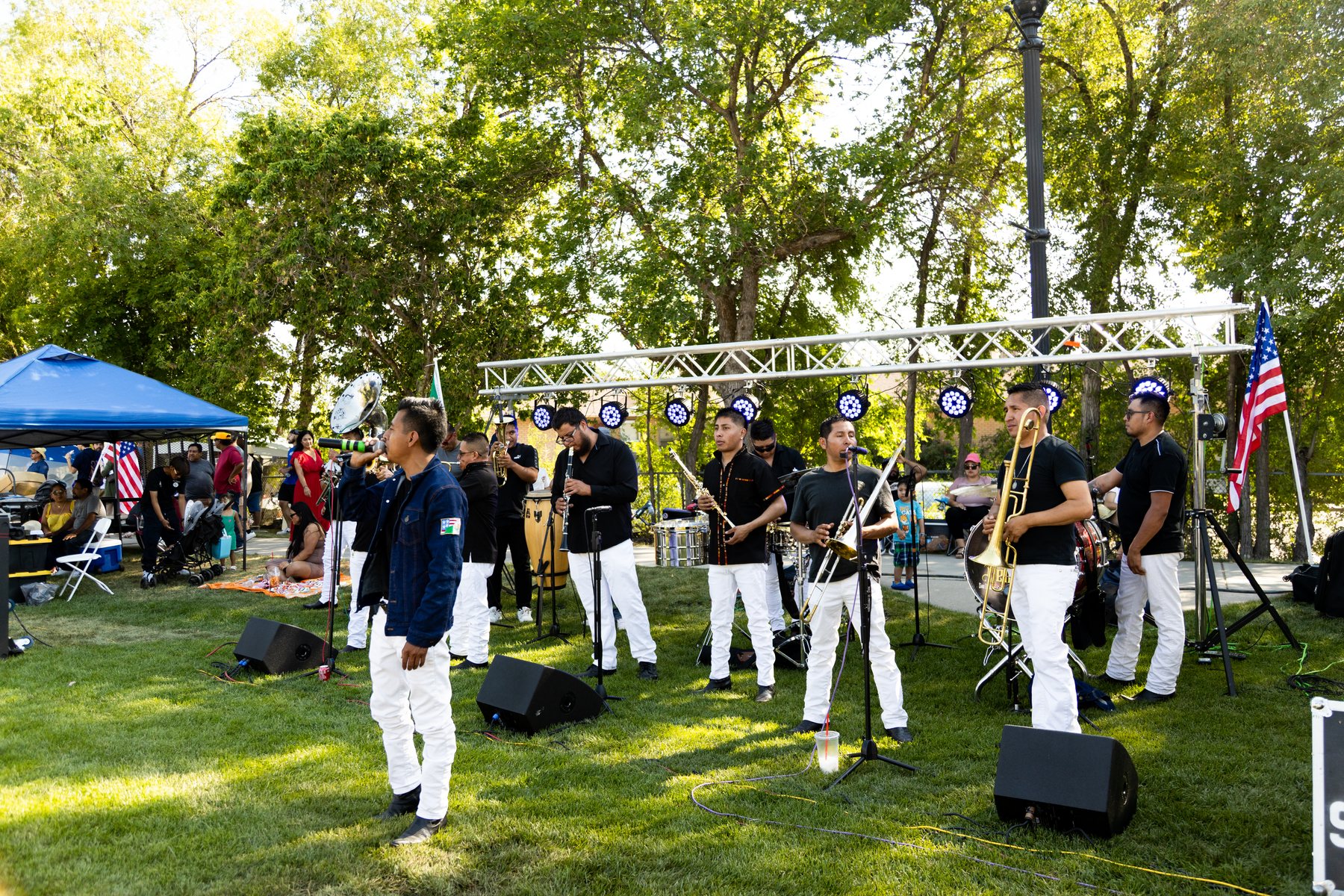 Un conjunto de metales con camisas negras y pantalones blancos toca bajo los árboles