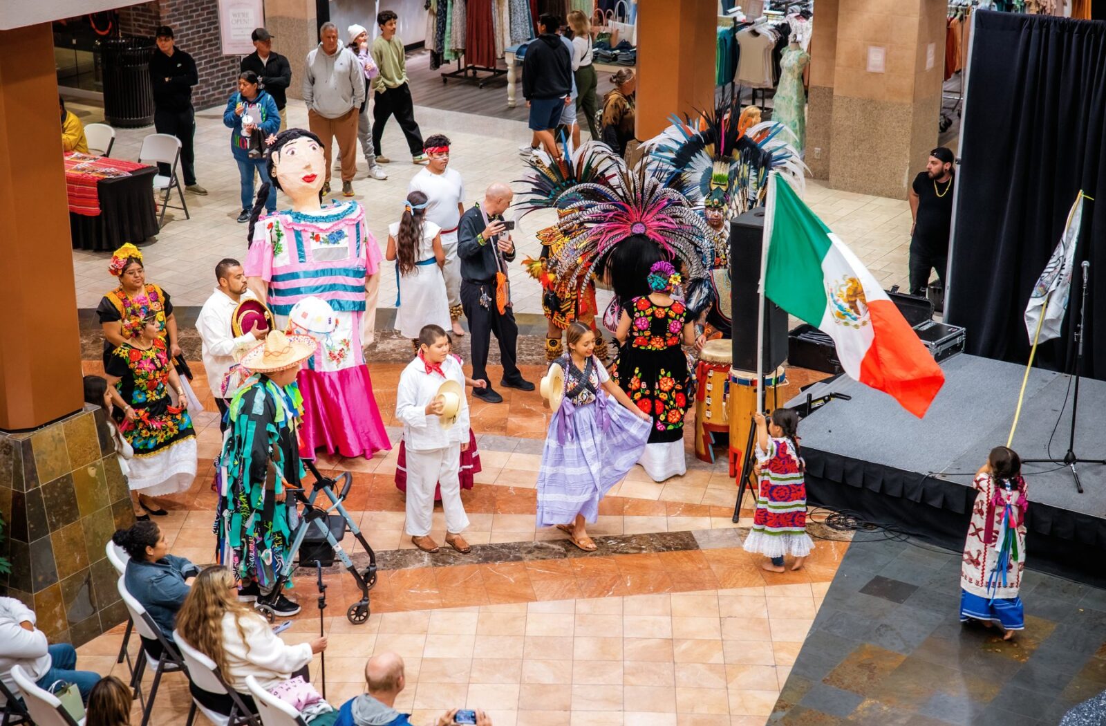 An overhead view of participants with a Mexican flag gathered beside the mall stage