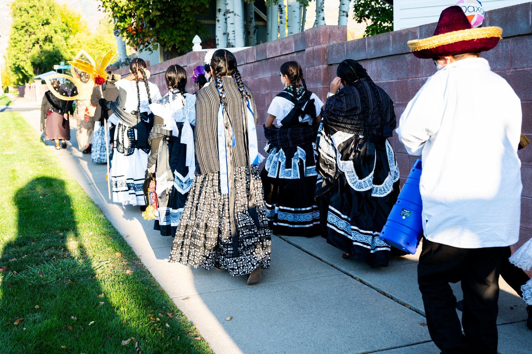 Un grupo con vestimenta negra, blanca y azul camina junto al muro del cementerio