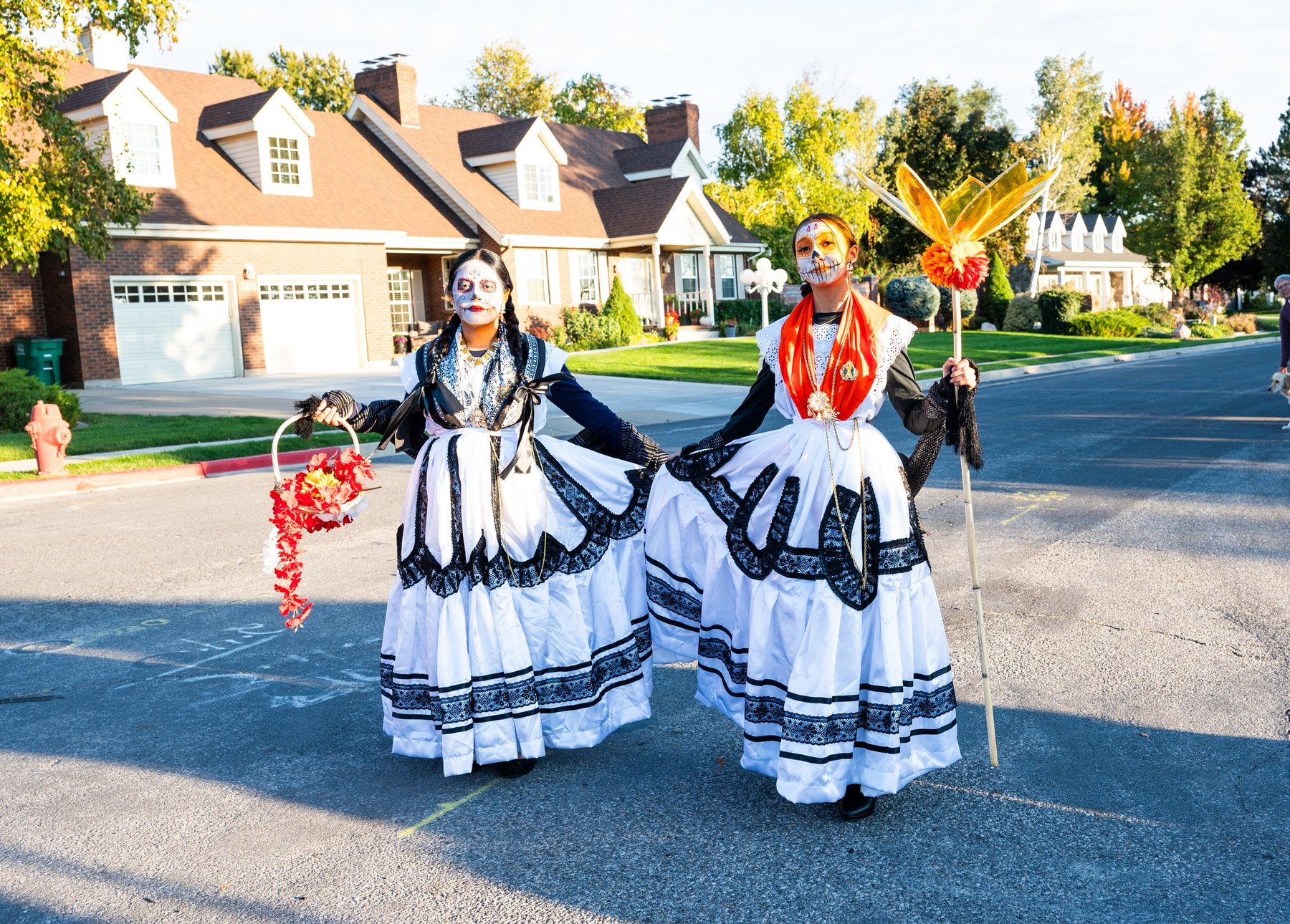 Dos participantes con vestidos negros y blancos están juntas en una calle residencial