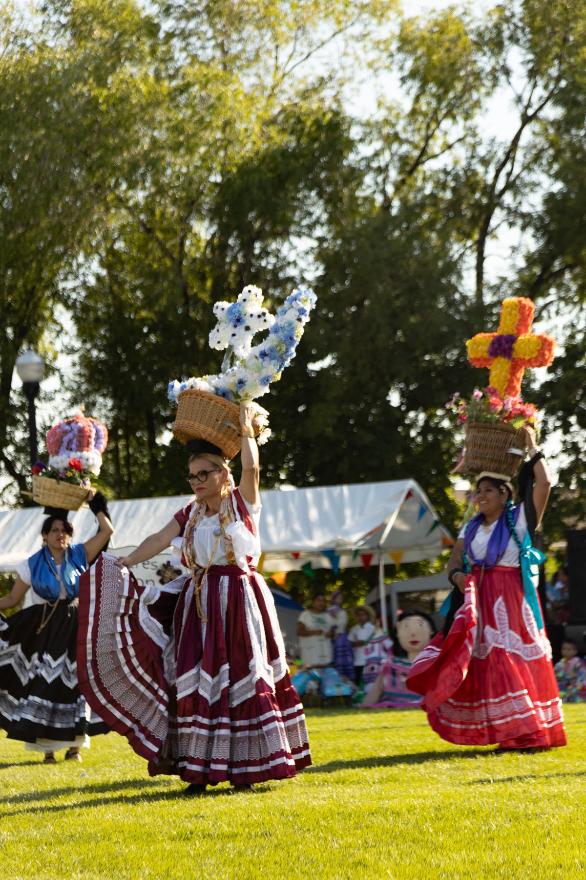 Cuatro participantes con faldas coloridas están sobre el césped iluminado del festival