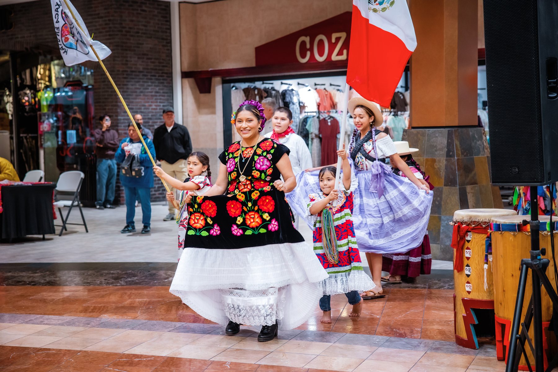 Una participante con blusa negra floral y falda blanca avanza hacia el público