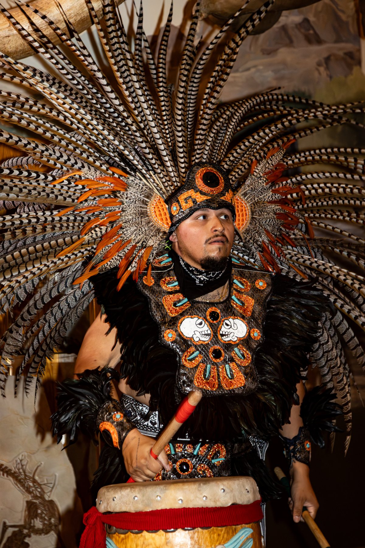 Un artista posa con un elaborado tocado de plumas y vestimenta con cuentas