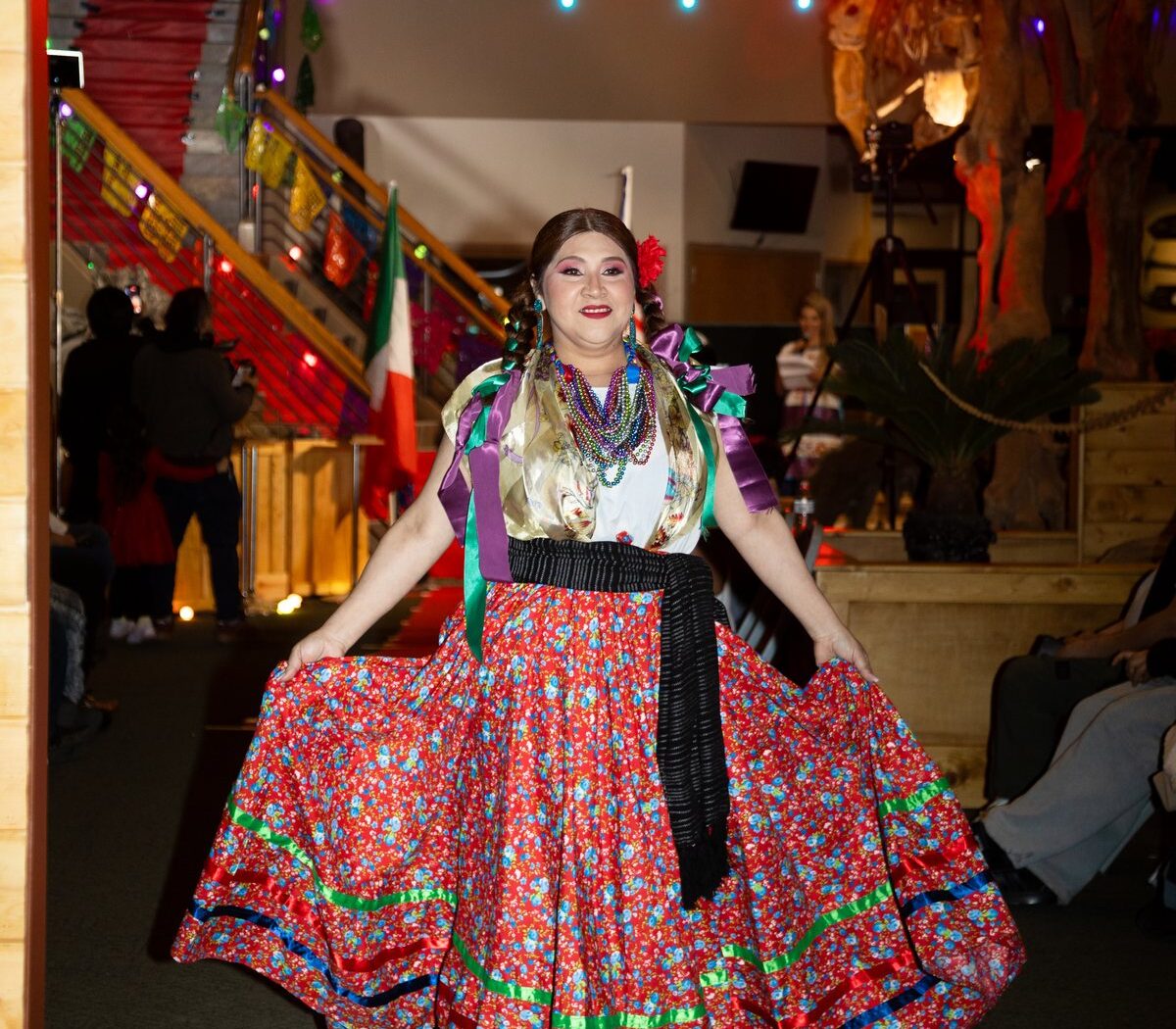 Una mujer presenta una amplia falda roja con flores en el Fashion Show 2026 de Oaxaca en Utah